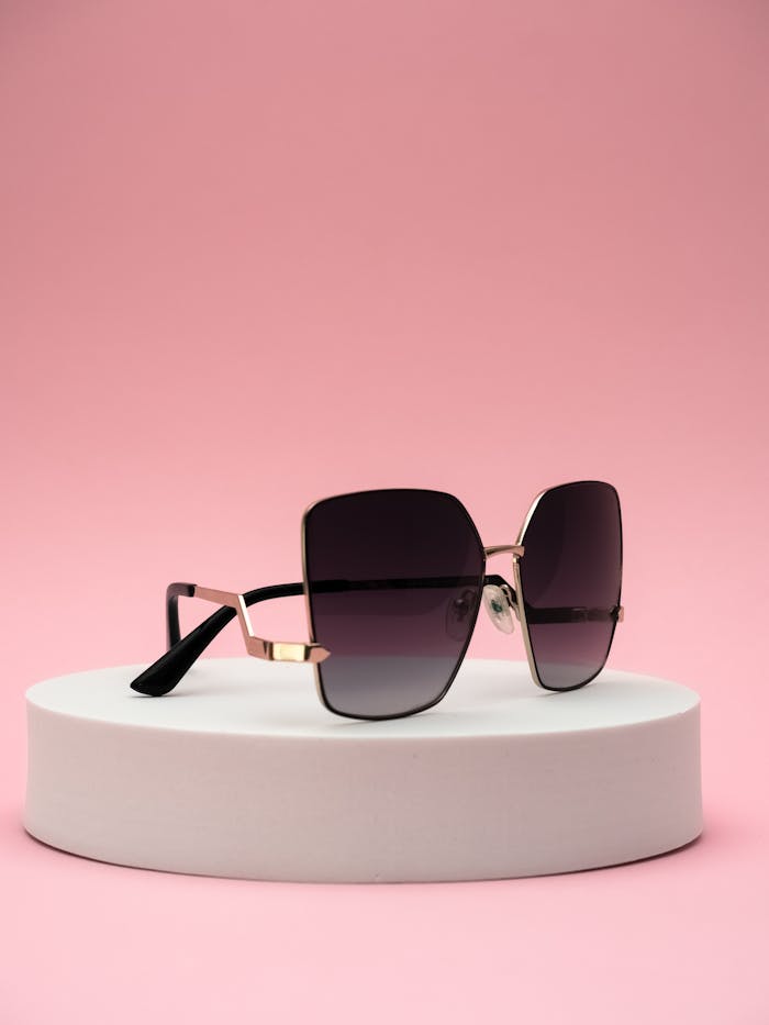 Luxury designer sunglasses displayed on a pink backdrop, showcasing style and fashion.